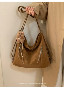 Close-up of brown vintage leather tote bag texture with zipper details and bear charm