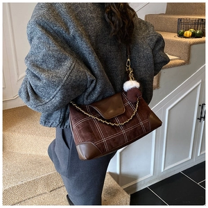 Brown suede dumpling bag with contrast stitching and golden chain detail shown on shoulder