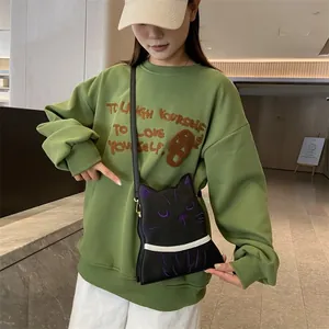 Détail d'un sac à bandoulière chat noir avec broderie violette porté par un mannequin