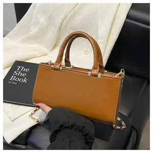 Close-up of a brown leather tote bag with dual handles and a gold chain strap
