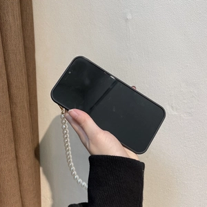 Detail of matte black iPhone case with white pearl strap handle and gold metal rings
