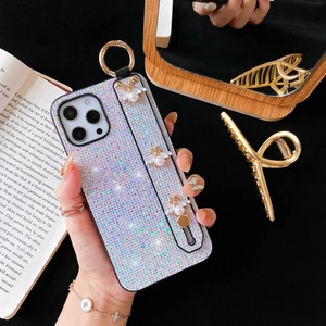 Detail of glitter iPhone case featuring gold bee charms and a pearl wrist strap handle