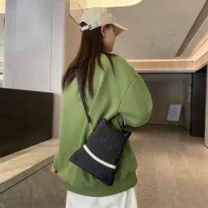 Détail d'un sac bandoulière chat avec coutures violettes et boucles dorées chic