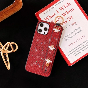Macro detail of red rhinestone iPhone case with luxury pearl bee charm and hand strap