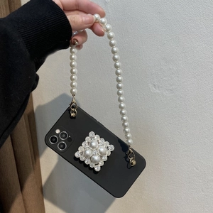 Detail of black matte iPhone case featuring diamond pearl decor and matching wrist strap