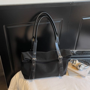 Détail d'un grand sac à bandoulière noir avec œillets argentés et détails en cuir