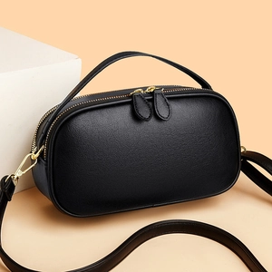 Premium black genuine leather crossbody phone bag with gold hardware on warm background