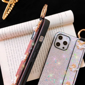 Close-up of glitter iPhone case featuring a pearl wristband and a golden bee charm