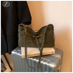 Close-up of dark green matte tote bag featuring vintage bronze turn-lock on metal suitcase