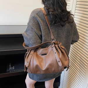 Brown litchi leather tote bag with drawstring design and metallic accents for women