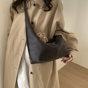 Minimalist coffee brown crescent shoulder bag with plush bear charm on stylish model