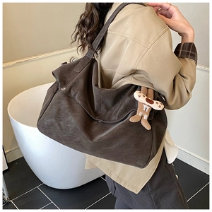 Detail of dark brown faux suede tote bag featuring a cute gingerbread man plush charm