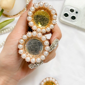 Close-up of pearl-encrusted folding phone socket held by hand in elegant setting