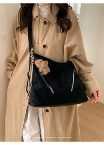 Detail of vintage black tote bag with silver zippers and a cute brown plush bear charm