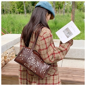 Detail of dark brown leather underarm bag featuring vintage silver rivet embellishments