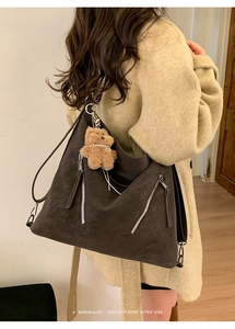 Detail of vintage brown tote bag with decorative zippers and a plush bear pendant charm