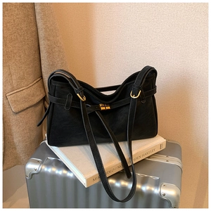 Detail of black matte tote bag with gold buckle on a stylish travel-themed background
