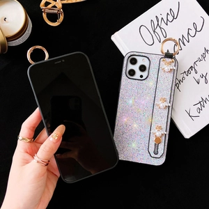 Close-up of glitter iPhone case with pearl bee wrist strap and gold metal ring hook