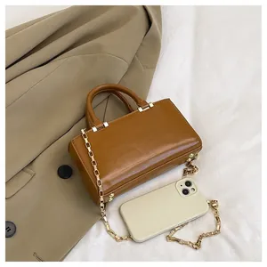 Detail of vintage brown tote bag with metal chain strap and round handles on trench coat