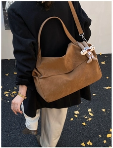 Brown large capacity suede tote bag with cute bunny pendant shown in a lifestyle street shot