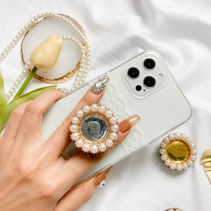 Close-up of elegant pearl foldable phone stand with gold base on a glitter phone case