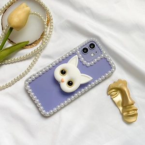 Close-up of purple iPhone case with pearl trim and 3D cat grip on white fabric