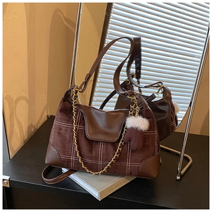 Detail of plaid shoulder bag featuring brown leather trim and cute glove charm accessory