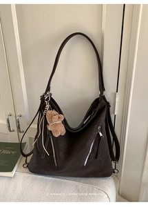 Close-up of brown matte leather tote bag with double zippers and plush bear charm