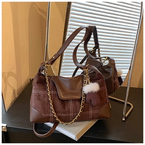Detail of coffee brown plaid suede bag featuring gold chain and plush glove charm