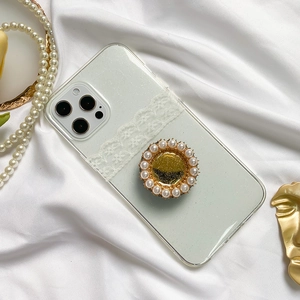 Detail of white lace phone case with pearl-rimmed glitter socket on silk background