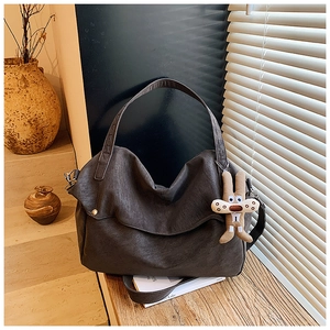 Detail of taupe tote bag with vintage leather texture and cute plush rabbit charm accessory