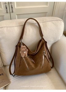 Detailed texture of brown retro faux leather bag with silver zippers and plush bear charm