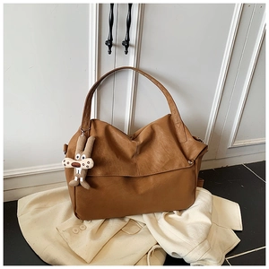 Close-up of brown leather tote bag with soft texture and cute rabbit plush charm