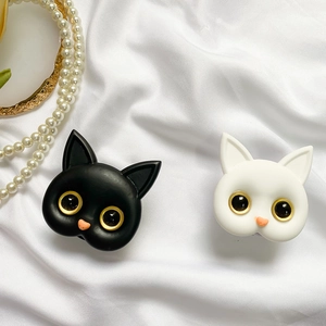 Detail of cute cat phone grips in black and white with gold eyes on silk fabric
