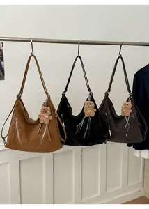 Detailed view of large hobo bags in brown and black with bear charms and metal zippers