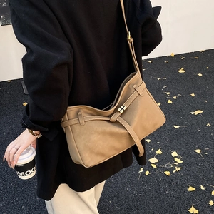 Minimalist khaki leather tote bag with gold buckle shown in an autumn street scene