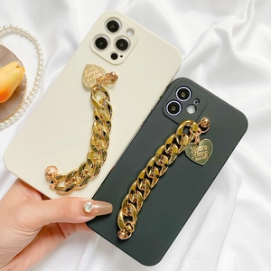Detail of iPhone silicone case featuring chunky gold chain handle and heart charm pendant