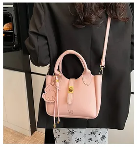 Detail of pink lychee textured leather handbag featuring gold twist lock and dog charm
