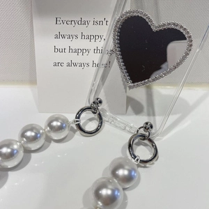 Detail of transparent phone case with heart mirror and large pearl wrist strap