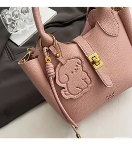 Detail of pink lychee leather handbag with gold twist lock and dog-shaped charm