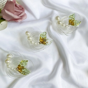 Macro shot of heart-shaped glitter phone grips with pearls and mermaid tails on silk