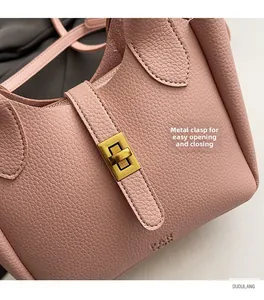 Detail of pink lychee leather texture and golden metal swivel lock closure on the bag