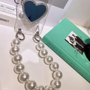 Detail of transparent phone case with pearl chain strap and sparkling heart mirror