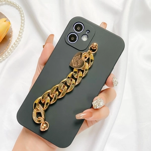 Detail of matte black phone case with chunky gold chain strap and heart charm on silk