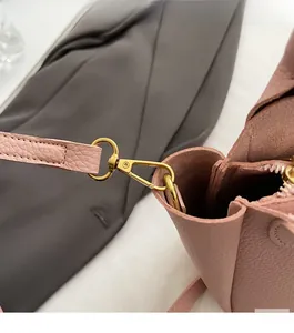 Close-up of pink litchi grain leather texture and durable golden metal strap hook