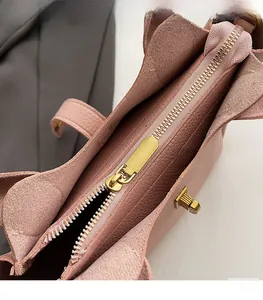 Detailed macro view of the smooth gold metal zipper and pink litchi grain leather bag