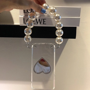 Detail of transparent phone case featuring a pearl handle and heart-shaped vanity mirror