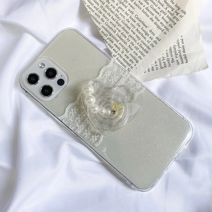 Detail of glitter heart phone grip with pearls and sequins on lace case over vintage paper
