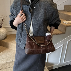 Brown suede dumpling bag with white grid pattern and plush charm on a model