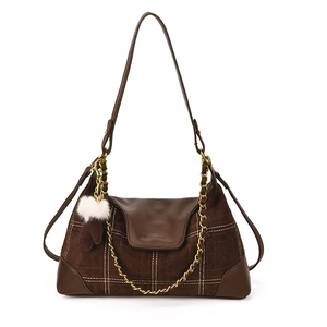 Brown dumpling-shaped shoulder bag with grid stitching and plush ball charm in front view
